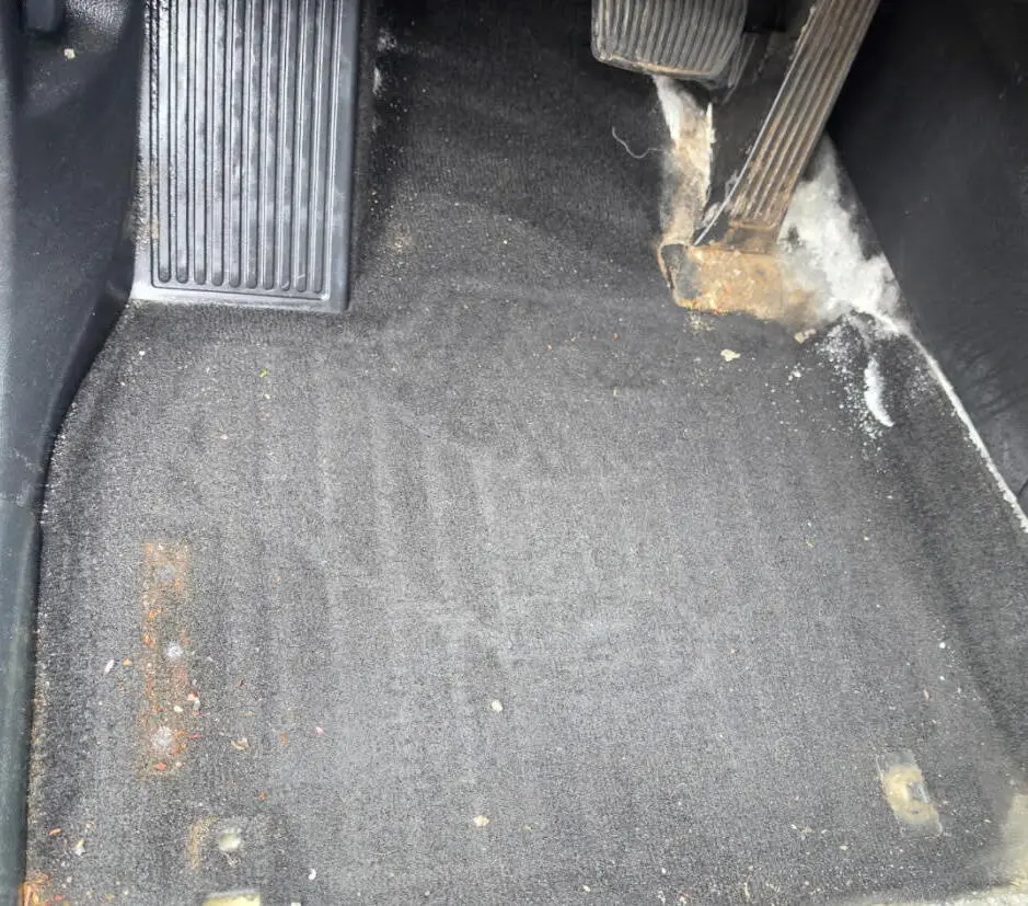 vehicle footwell carpet before detailing, covered in road salt and debris